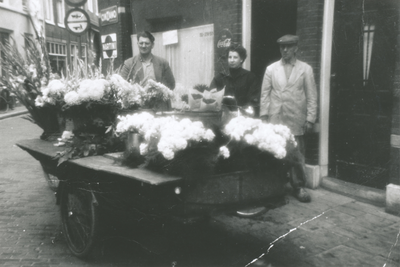 875275 Portret van het echtpaar Veenendaal-van Zuilen bij hun bloemenkar op de hoek van de Rozenstraat en de ...